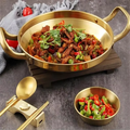 Golden stainless steel wok pan with handles filled with stir-fried meat and vegetables, accompanied by matching serving bowl 