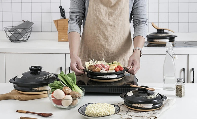 Earthenware clay casserole pot with wooden lid being used to cook colorful vegetables in modern kitchen setting, demonstratin
