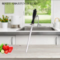 Stainless steel knife sharpener rod with black grip handle displayed on wooden cutting board in bright kitchen with fresh veg