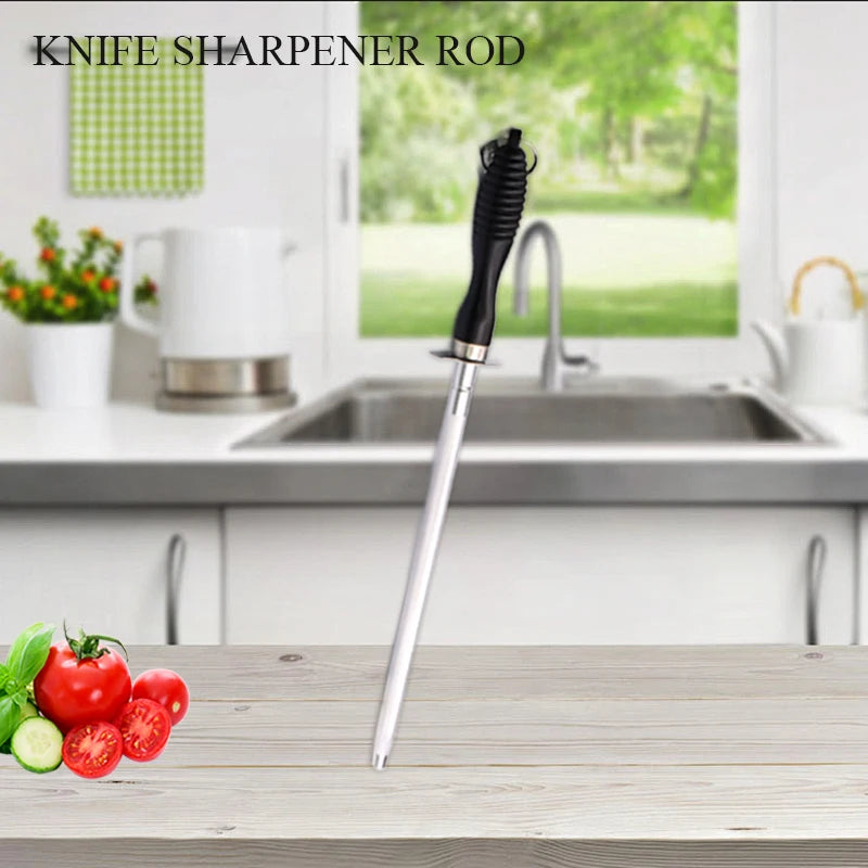 Stainless steel knife sharpener rod with black grip handle displayed on wooden cutting board in bright kitchen with fresh veg
