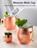 Copper Moscow Mule cups with hammered finish, gold handles, filled with ice and mint garnish, demonstrating cold insulation c