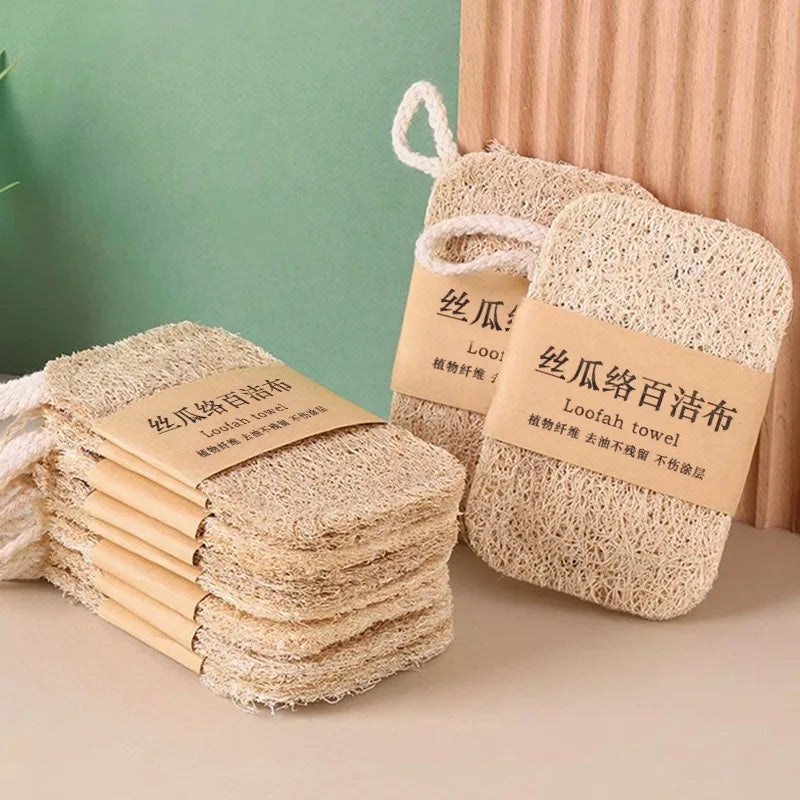Natural loofah dish scrubbers with rope handles, displayed in tan/beige color against green and peach background with product