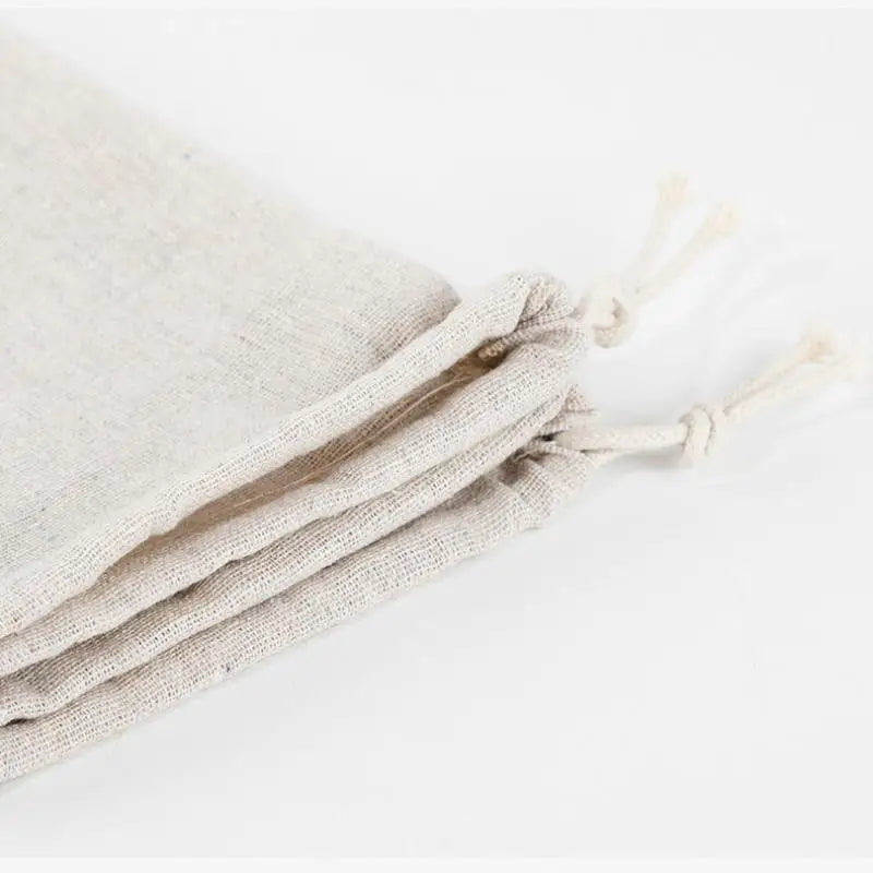 Handmade organic linen bread bags with drawstring closures, displayed in natural cream color for sustainable loaf storage.