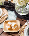 Eco-friendly palm leaf plate holding powdered lemon bars, styled on table with natural décor and white flowers.