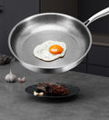 Pure Titanium Heritage Fry Pan with fried egg, showcasing natural non-stick surface and textured cooking area, with garlic an