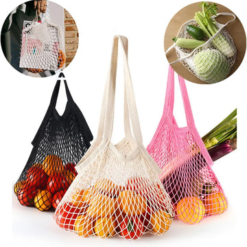 Three colorful cotton mesh produce bags in black, cream, and pink, filled with fresh vegetables and fruits, displayed against