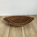 Hand-woven rattan bread basket with natural golden-brown weave and curved sides, displayed on wooden surface.
