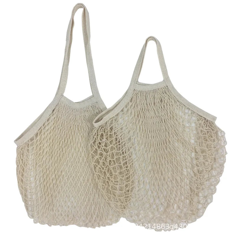 Two natural cotton mesh grocery bags with long handles, ideal for carrying vegetables and produce at market in an eco-friendl