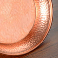 Pure copper serving plate with hammered rim detail and polished center surface, artisanal handcrafted design for eco-consciou