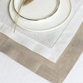 Elegant stacked white and natural linen dinner napkins with decorative hemstitching detail and dried wheat accent