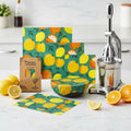 Beeswax food wrap set with citrus pattern, organic cotton covers, sustainable food storage with bowl demo holding tomatoes.