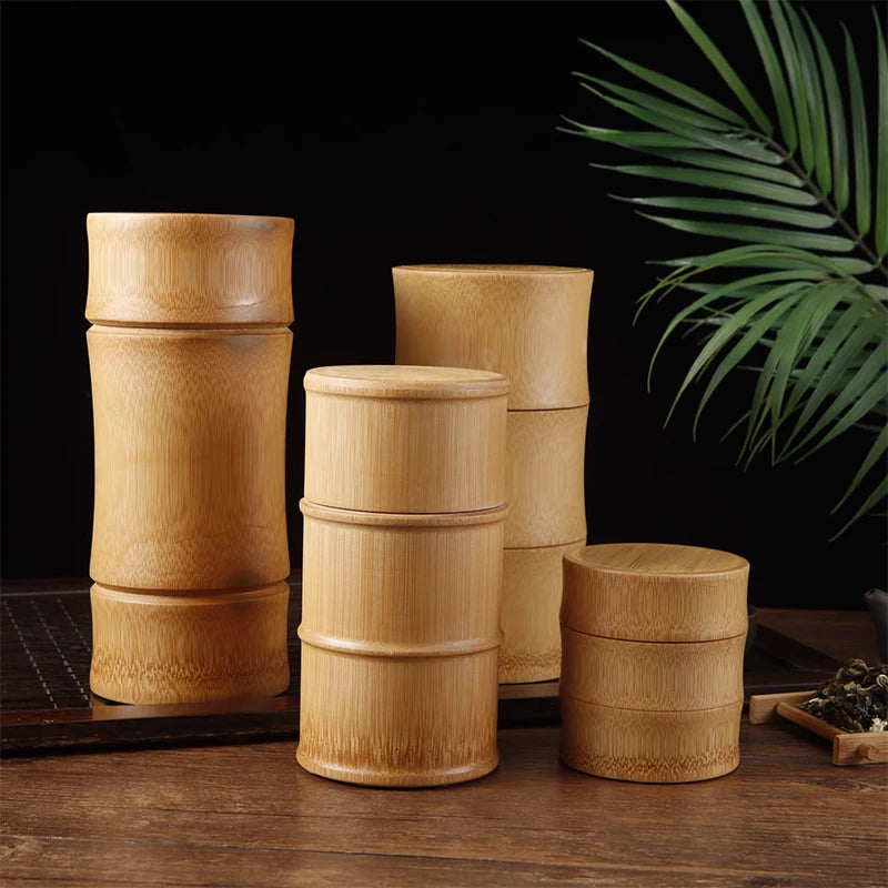Set of four cylindrical bamboo storage containers with natural wood finish and band details, displayed on wooden surface with