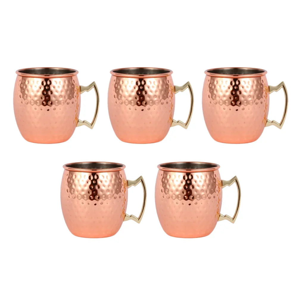 Set of 5 hammered copper Moscow mule mugs with brass handles and stainless steel interiors, displayed against white backgroun
