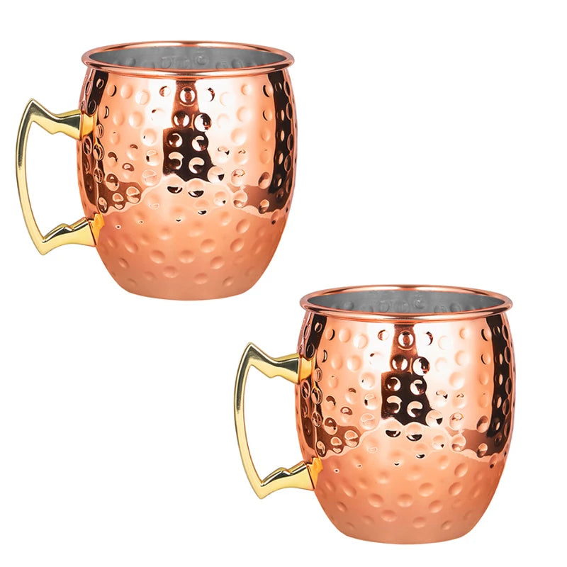 Two hammered copper Moscow Mule mugs with brass handles and stainless steel linings, displayed against white background.