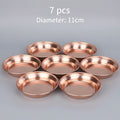 Seven handcrafted copper dining plates arranged on black surface, 18cm diameter, showing polished red copper finish and refle