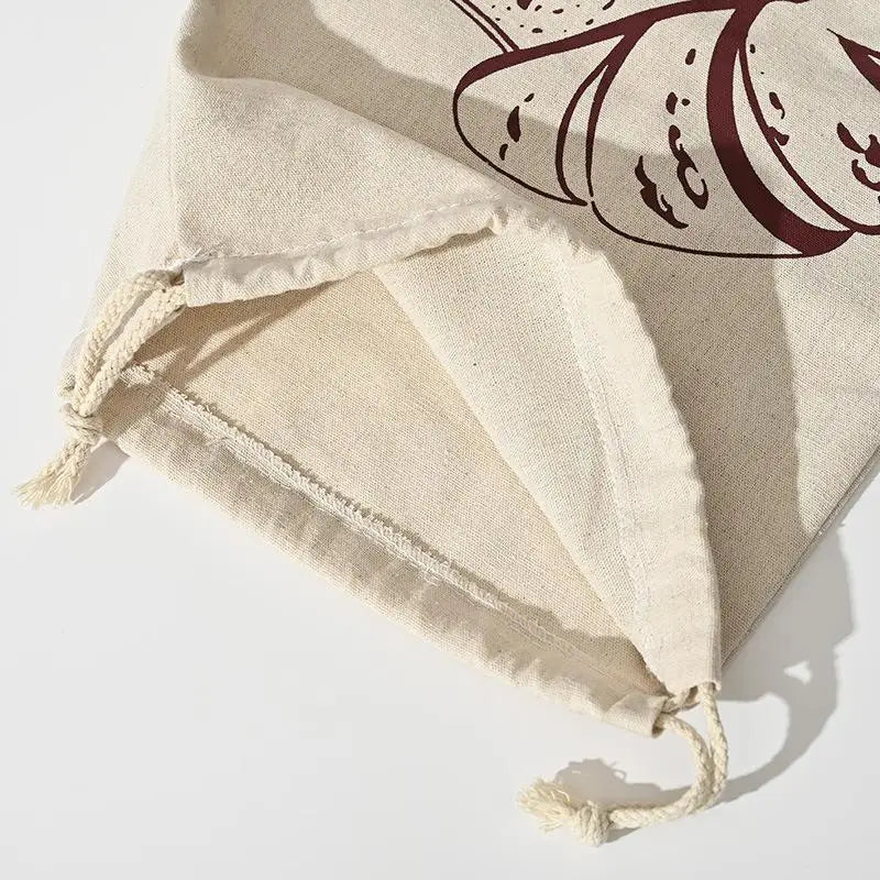Handmade organic linen bread bag with burgundy drawstring, displayed flat showing natural cream fabric and reusable loaf stor