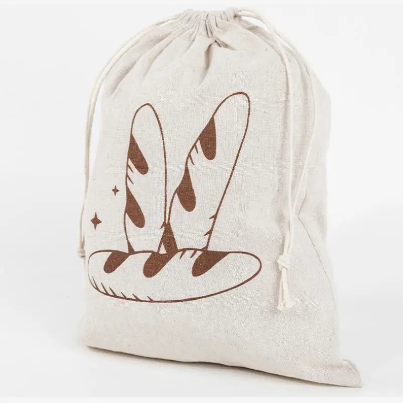 Handmade organic linen bread bag with brown baguette illustration and drawstring closure for reusable loaf storage.