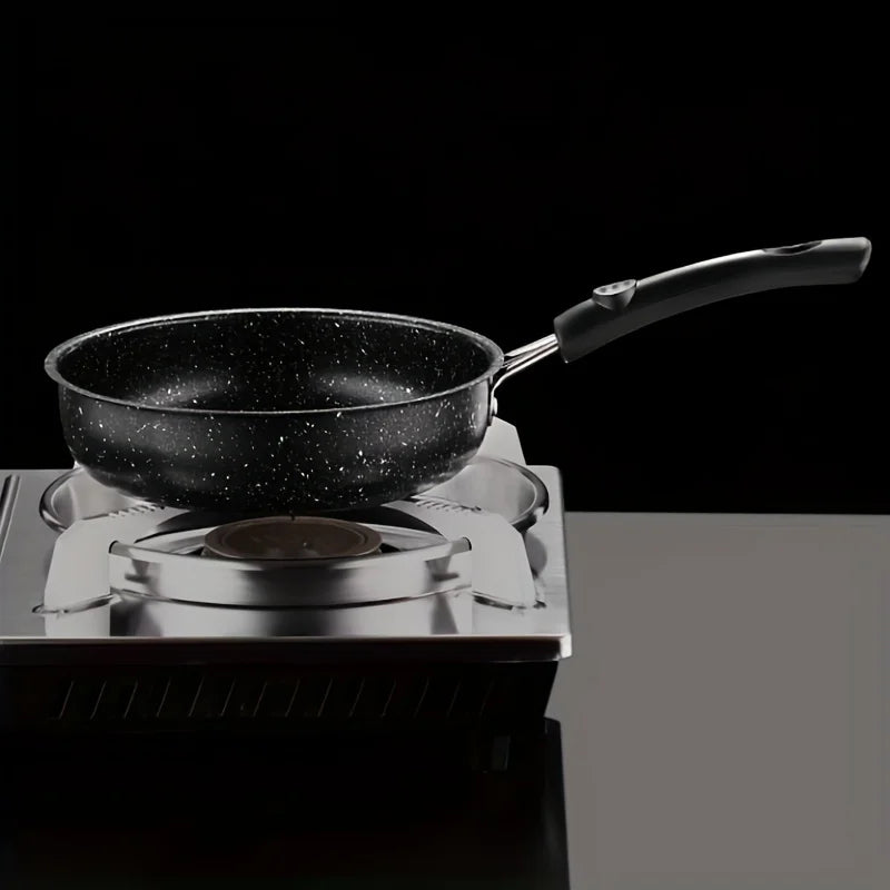 Black speckled non-stick skillet with handle on portable induction cooktop against dark background