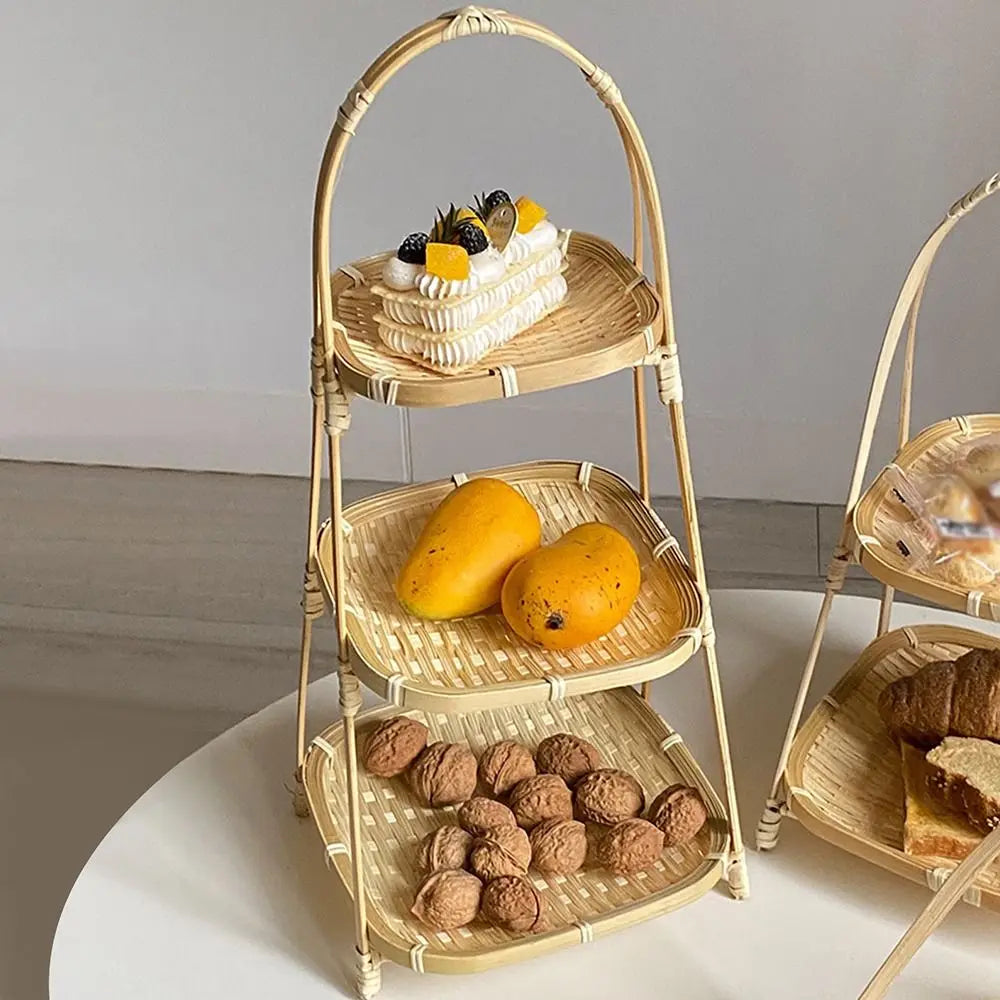 Three-tier bamboo basket stand holding walnuts, mangoes, and a cream dessert with berries on white surface.
