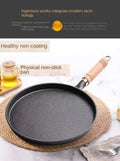Black cast iron skillet with wooden handle on marble surface, surrounded by oil and kitchen linens, showcasing non-stick cook