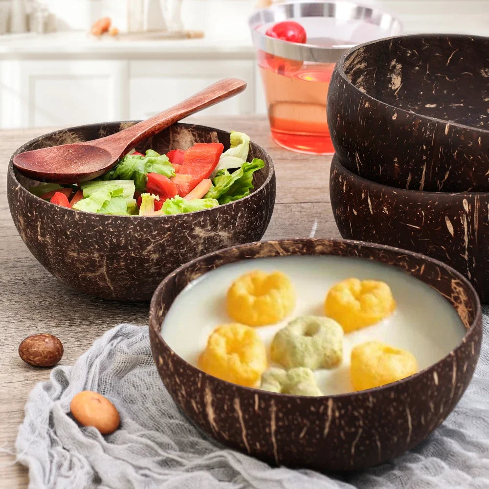 Handcrafted coconut shell serving bowls with natural wood spoon, filled with fresh salad and soup, on kitchen table.