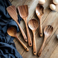 Wooden kitchen utensil set with spatula, spoon, and fork displayed on rustic wood surface with navy cloth and eggs.