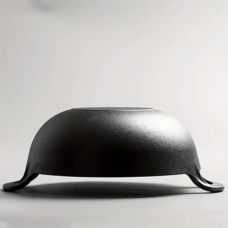 Black cast iron double-handle pot with curved dome lid, viewed from side profile against white background, showing sturdy coo