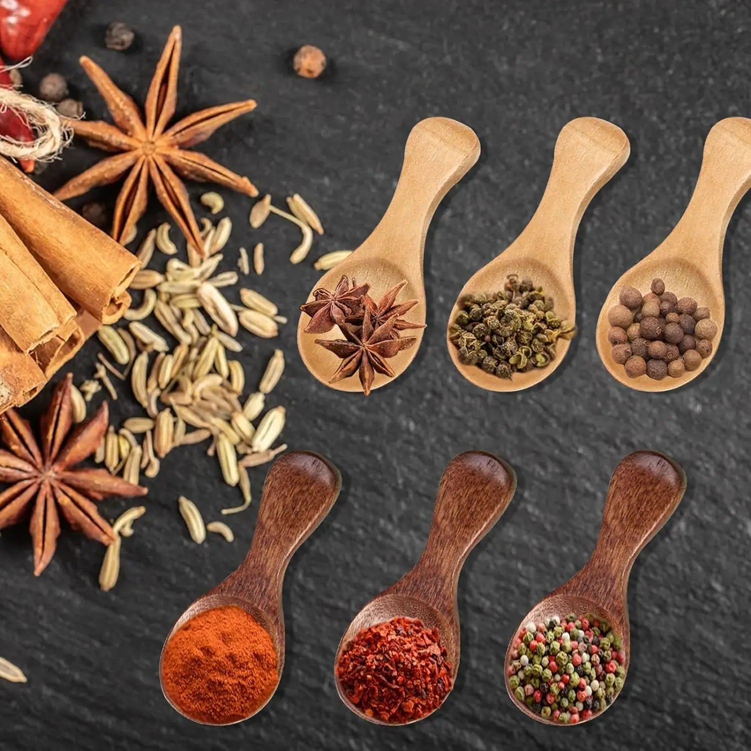 Bamboo mini scoop spoons displaying various spices and seasonings on dark surface with star anise and cinnamon.
