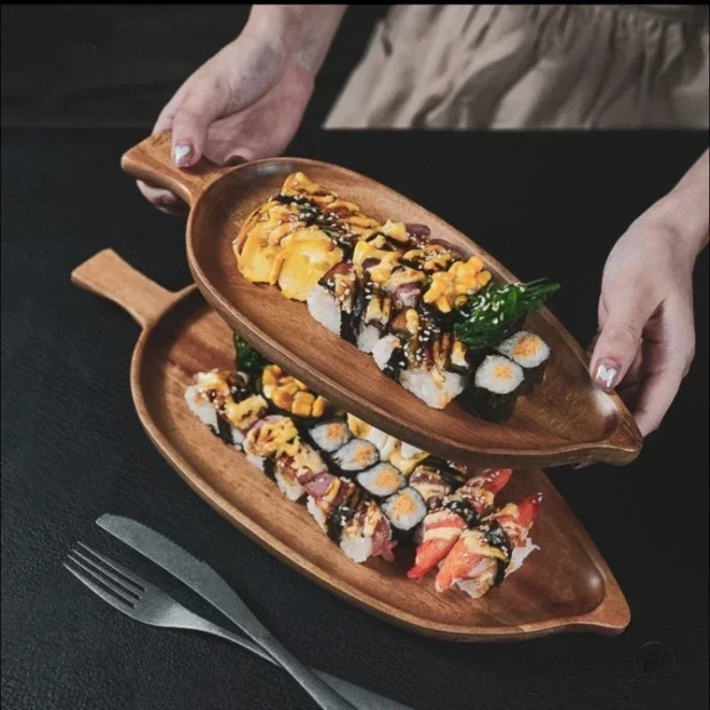 Wooden palm leaf-shaped sushi trays holding assorted sushi rolls with colorful toppings, displayed on dark surface with fork.