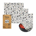 Beeswax food wrap set with organic cotton, featuring vegetable print design, shown wrapped around bowl with tomatoes and pack