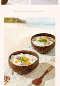 Natural coconut bowls with wooden spoons filled with creamy dessert, garnished with tropical fruits on sandy beach background