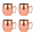 Set of four copper Moscow mule mugs with hammered finish, stainless steel interiors, and brass handles on white background.
