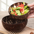 Handcrafted coconut shell salad bowl filled with fresh lettuce and red peppers, displayed on wooden surface with natural ligh