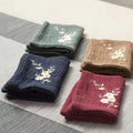 Organic cotton cleaning cloths in sage green, navy, brown, and burgundy with delicate embroidered daisy designs, displayed fo