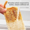 Natural loofah dish scrubber being rinsed under water, showing its dissolvable fibers and oil-free cleaning properties.