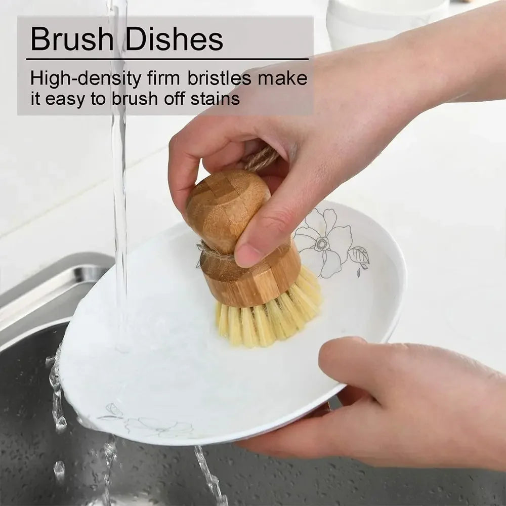 Wooden natural dish brush with coconut fiber bristles being used to clean a white plate under running water at a sink.