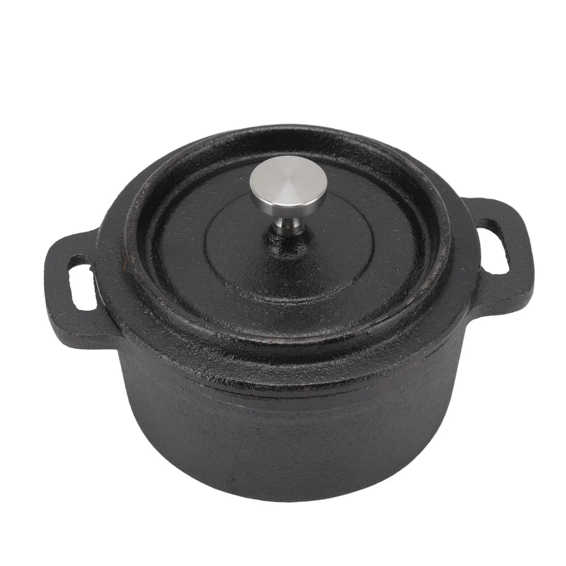Cast iron Dutch oven with lid surrounded by wooden bowls, glass herb jar, ceramic pitcher, and fresh herbs on concrete surfac