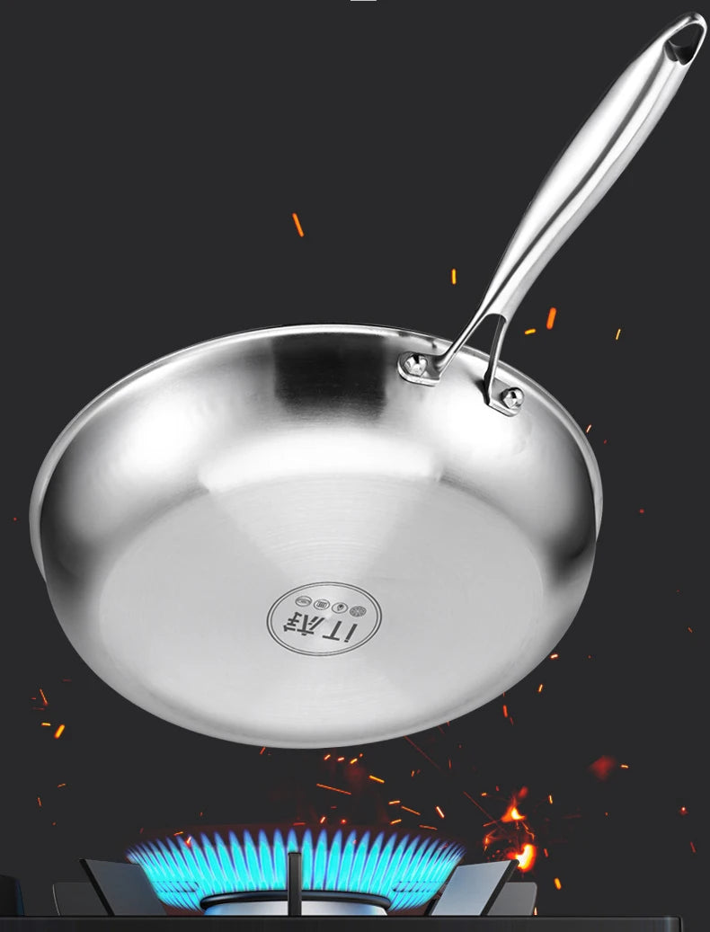 Pure titanium fry pan hovering over blue gas flame, showing natural non-stick surface and stainless steel handle against dark