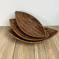 Hand-woven rattan bread baskets in natural brown, stacked nested display showing woven texture and oval leaf shape design.