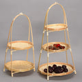 Two-tier bamboo baskets with arched handles, displaying dried fruits and berries, natural woven construction with rope accent