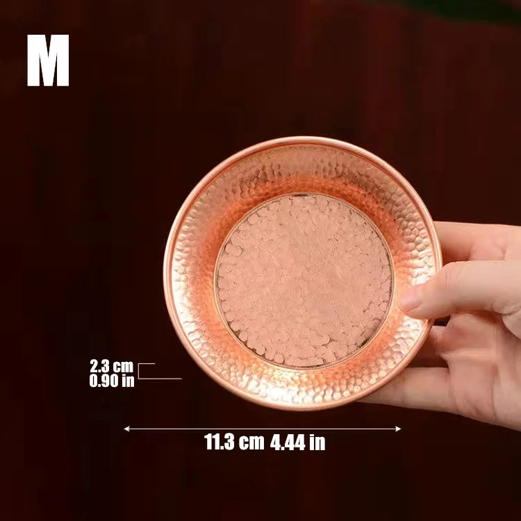 Pure copper serving plate with hammered texture held in hand, showing 11.3 cm diameter and artisanal craftsmanship for eco-fr