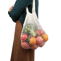 Cotton mesh grocery bag holding fresh produce in white, eco-friendly reusable market tote with handles