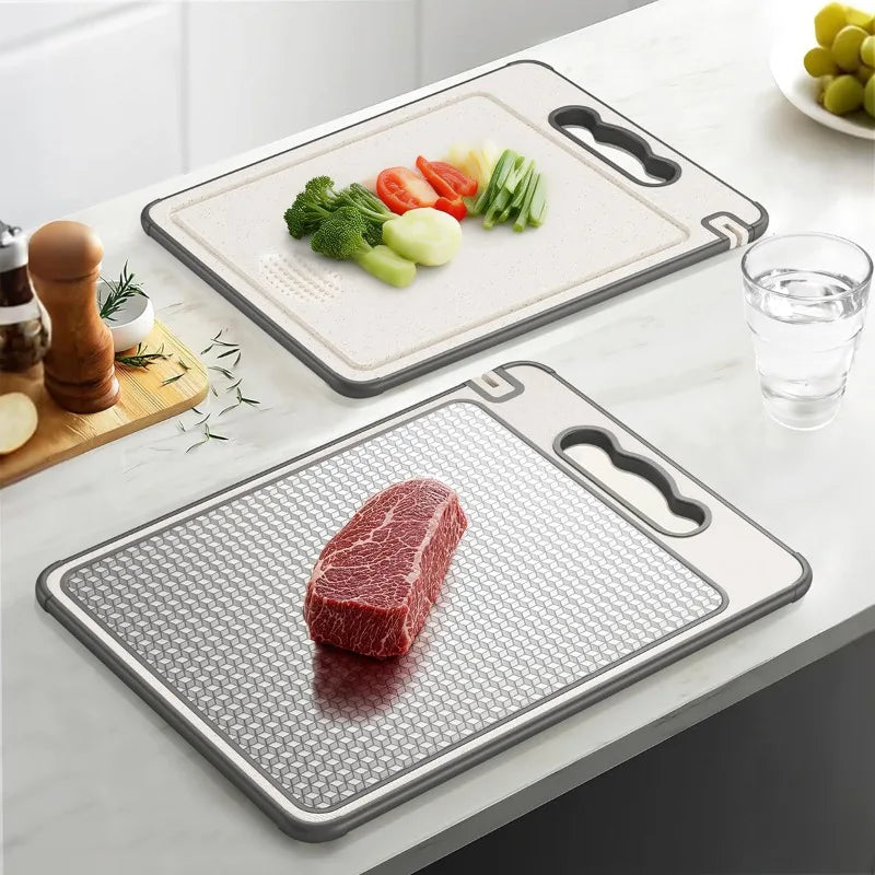 Two stainless steel cutting boards with slip-resistant surfaces; upper board displays fresh vegetables, lower board shows raw