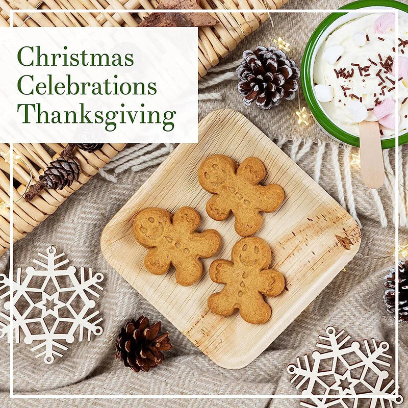 Eco-friendly palm leaf plates displaying gingerbread cookies, pinecones, and festive decorations on natural linen background.