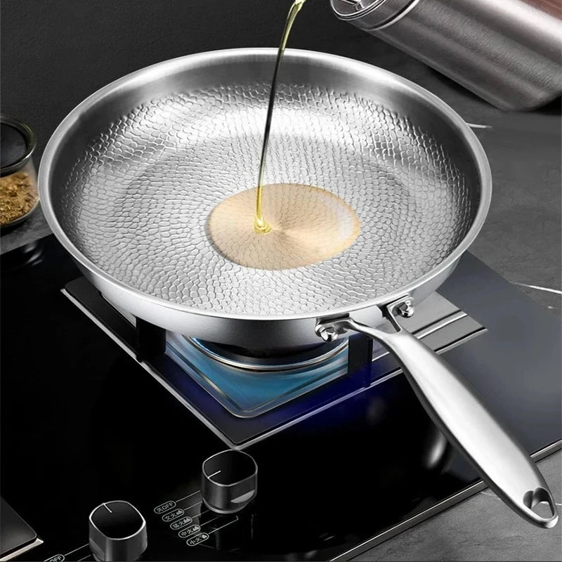 Pure titanium fry pan with oil being poured in, showing natural non-stick surface on induction cooktop, eco-friendly cookware