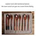 Wooden cutlery set with spoons, forks, and chopsticks arranged on striped linen cloth over wooden surface.