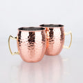 Two hammered copper travel cups with brass handles and dark interior lining on white background.