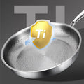 Pure titanium heritage fry pan with honeycomb texture surface and protective Ti shield badge, stainless steel handle against 