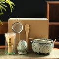 Japanese matcha tea set with bamboo whisk, wooden spoon, ceramic bowls, strainer, and matcha holder in eco-friendly kraft pac