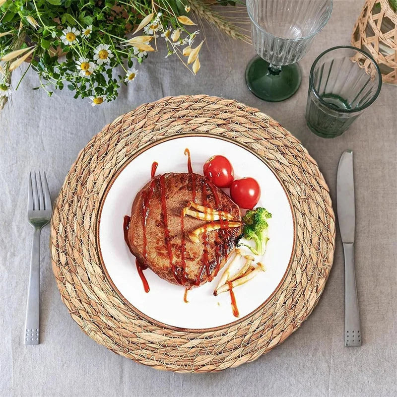 Handwoven rattan round placemat with white ceramic plate displaying creative food art, flanked by fork and knife on neutral l